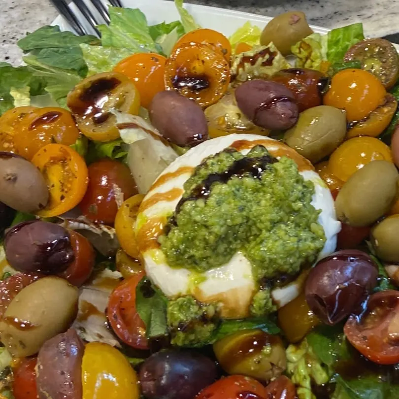 Rig A' Tony's Italian salad with burrata, pesto, cherry tomatoes, olives, and balsamic glaze.